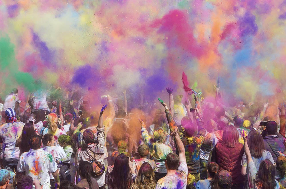 People at a concert facing the stage with various colours of paint powder in the air